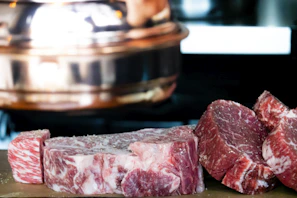 Close-up of premium marbled beef steaks on a dark wooden board with fresh herbs.