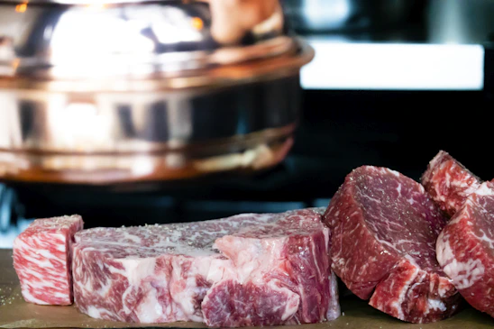 Cinematic close-up of marbleized Wagyu beef on a rustic wooden board with soft natural light highlighting texture.
