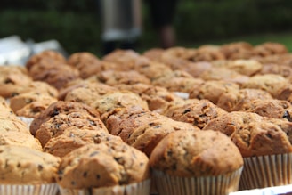 An assortment of golden-brown, freshly baked muffins arranged on a rustic wooden tray.