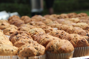 An assortment of golden-brown, freshly baked muffins arranged on a rustic wooden tray.