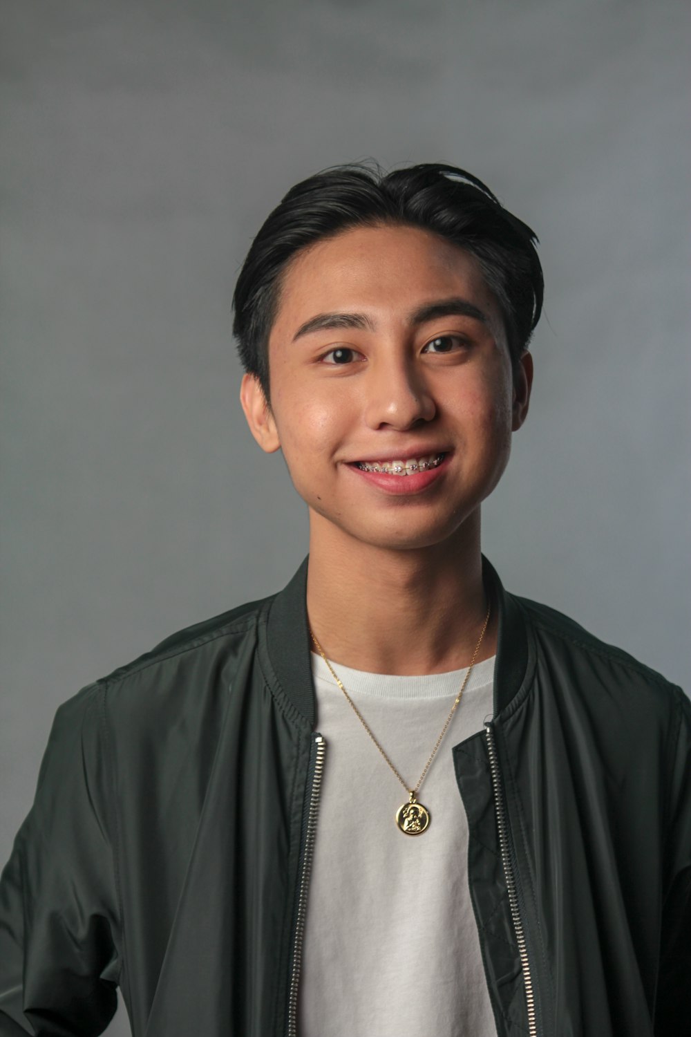 man wearing black zip-up bomber jacket while smiling