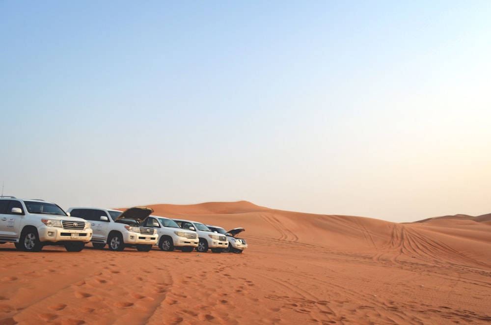 Fünf weiße Fahrzeuge in der Wüste geparkt