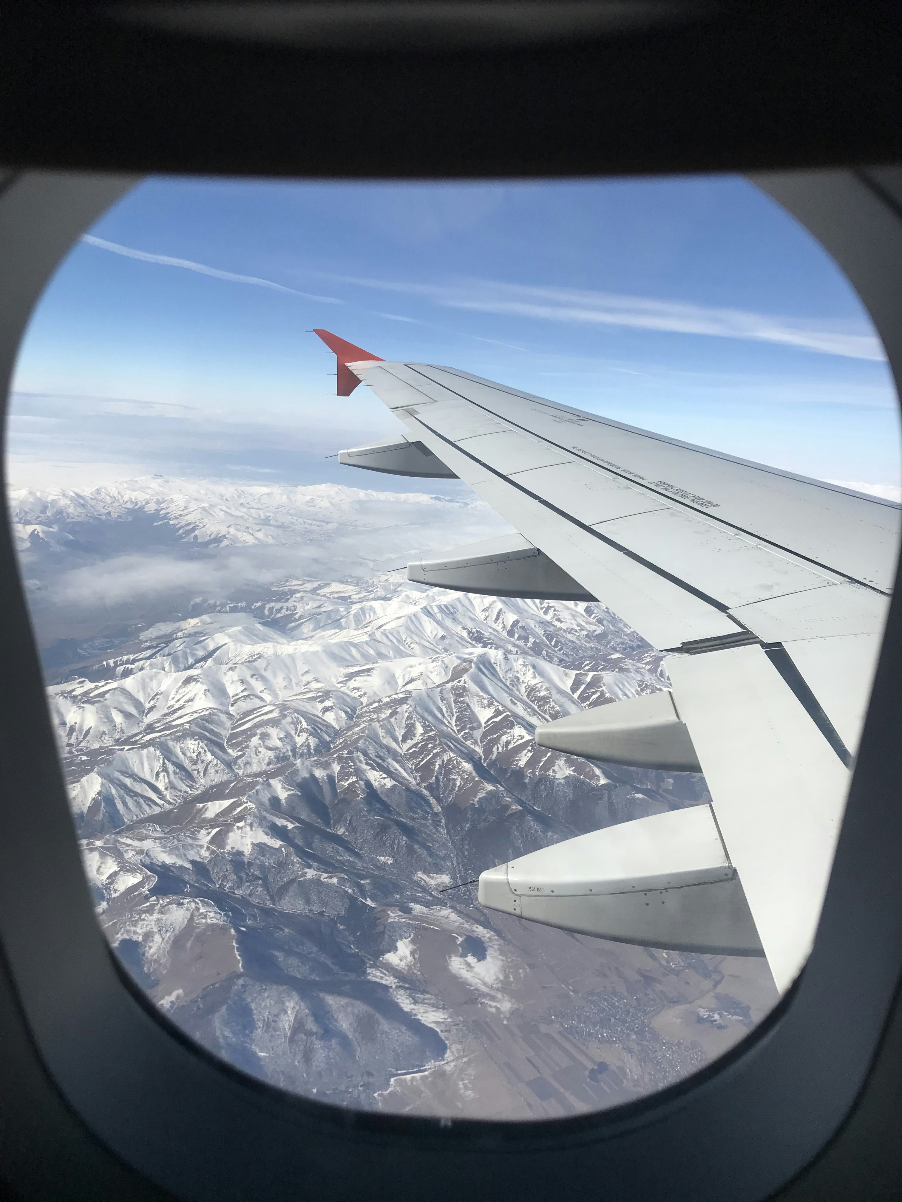 Airplane flying near mountains during daytime photo Free Blue Image