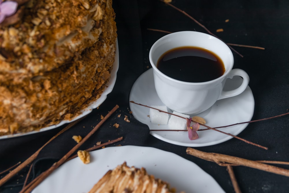 cup of black coffee on saucer beside cake