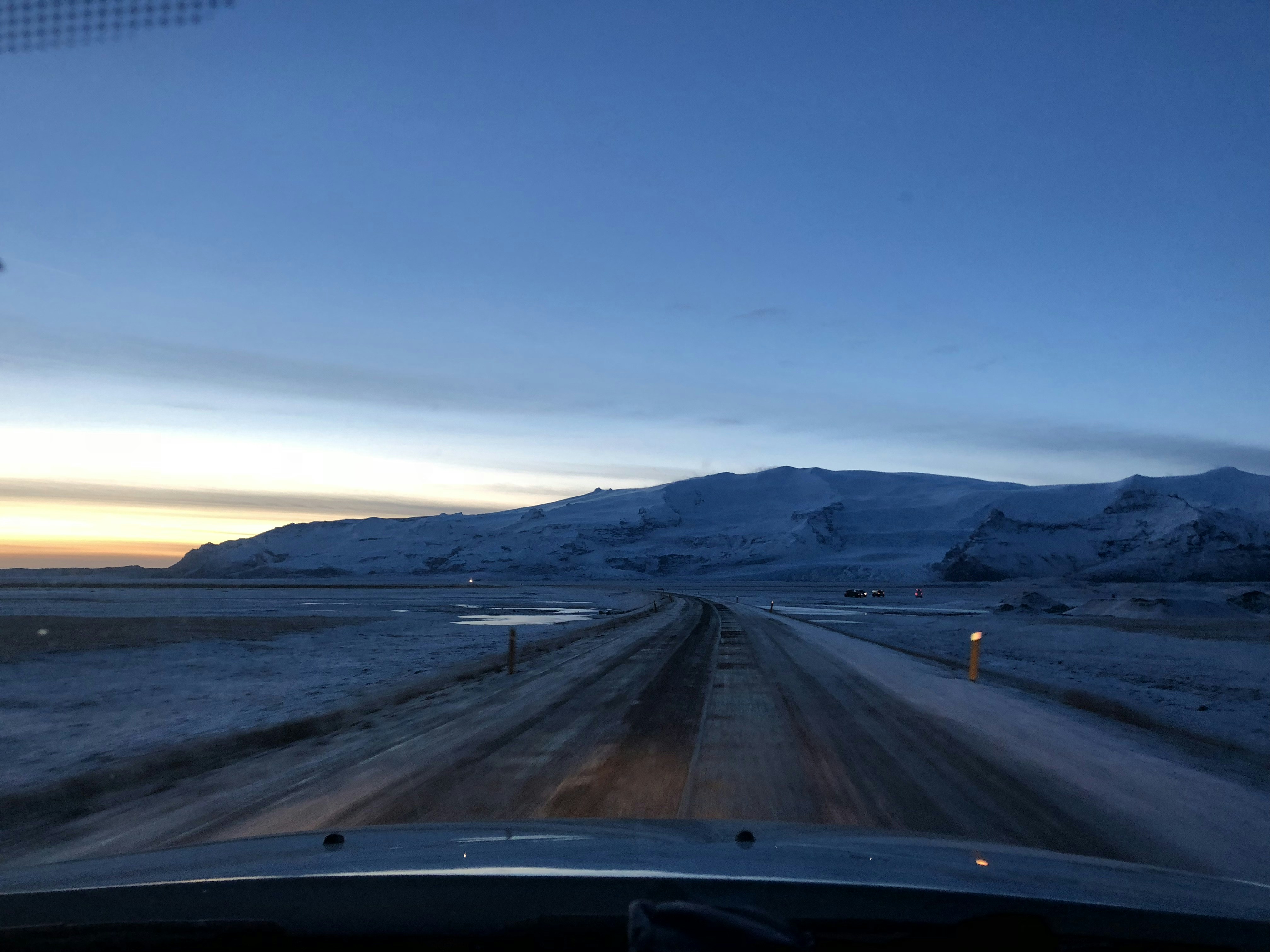 gray concrete road viewing mountain under blue and white sky during daytime