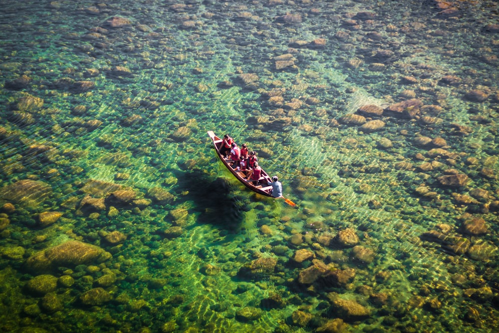 people on wooden boat sailing on clear water