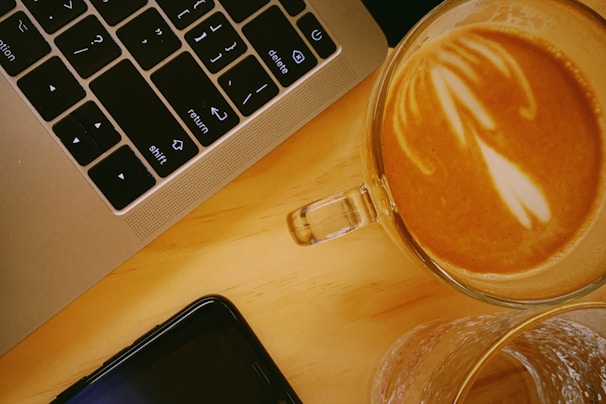 Close-up of hands typing on a keyboard with coffee cups nearby, capturing a focused work session.