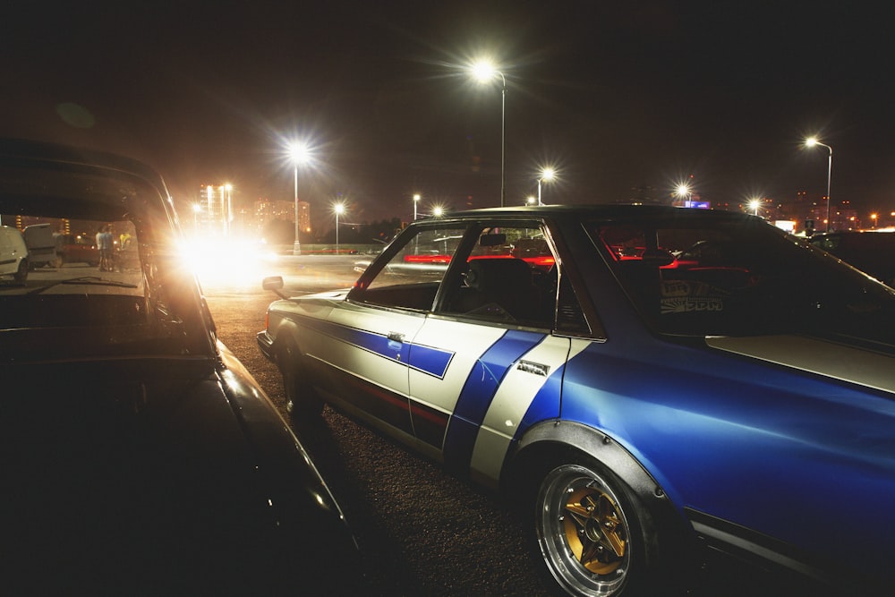 gray and blue sedan parked beside another vehicle at night