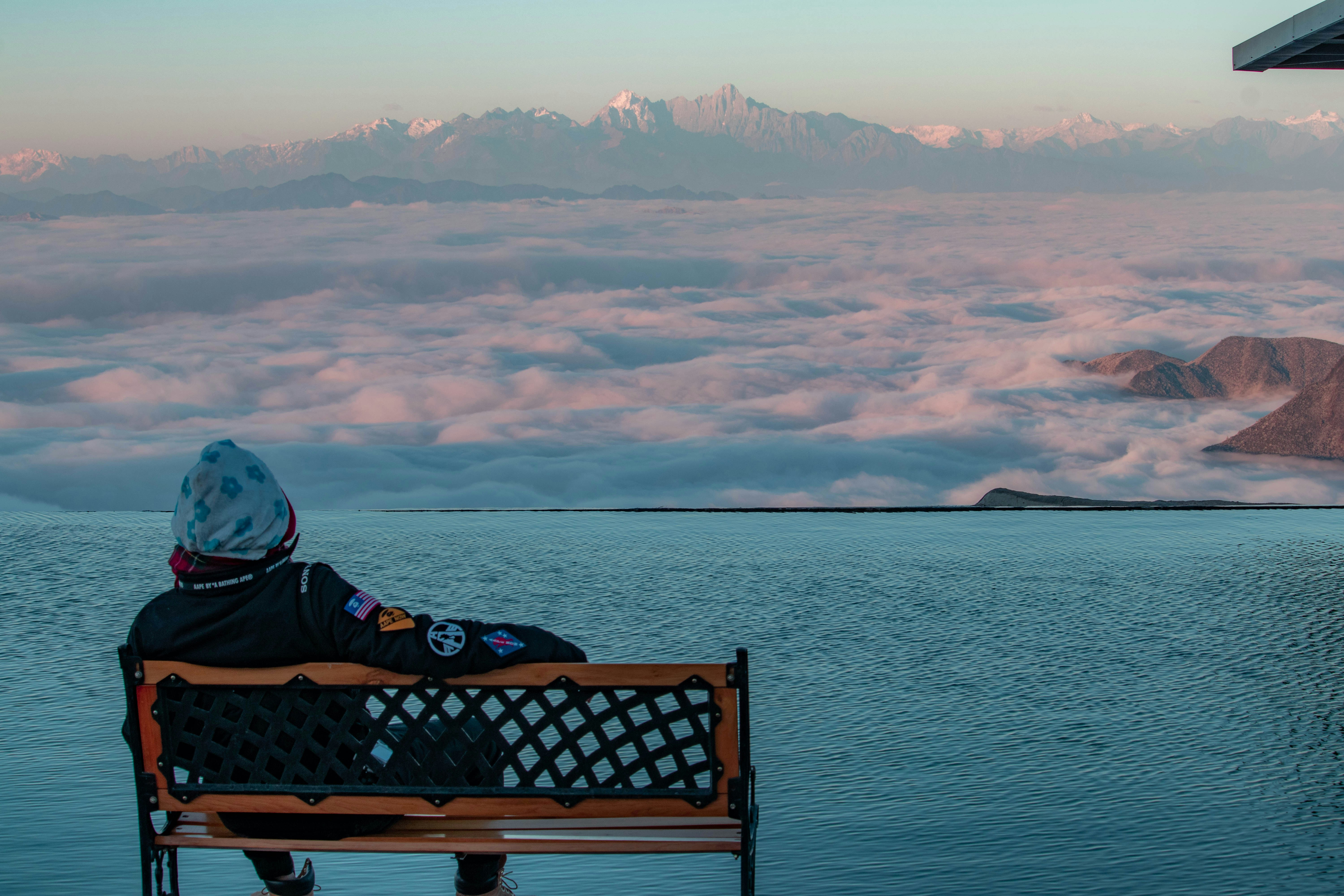 person sitting on bench facing blue sea