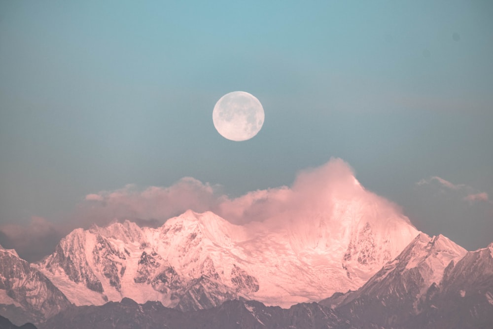 雪をかぶった山脈の上の丸い月