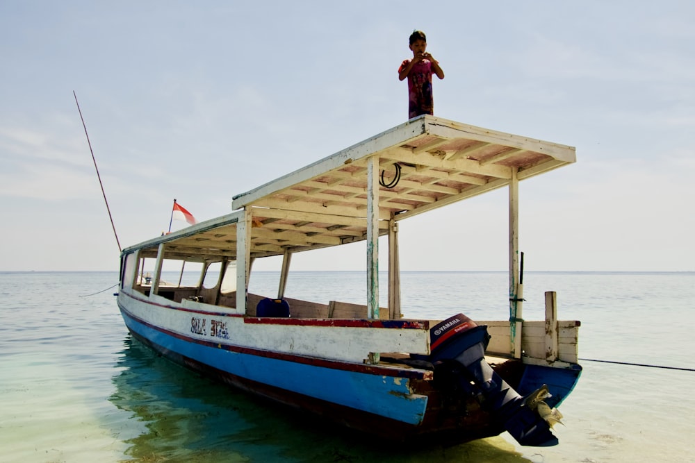 person standing on boat roof on water during daytime