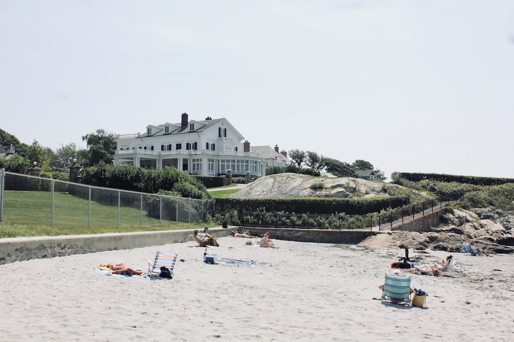 people lying and sitting on sand beside gray chain link fence during daytime