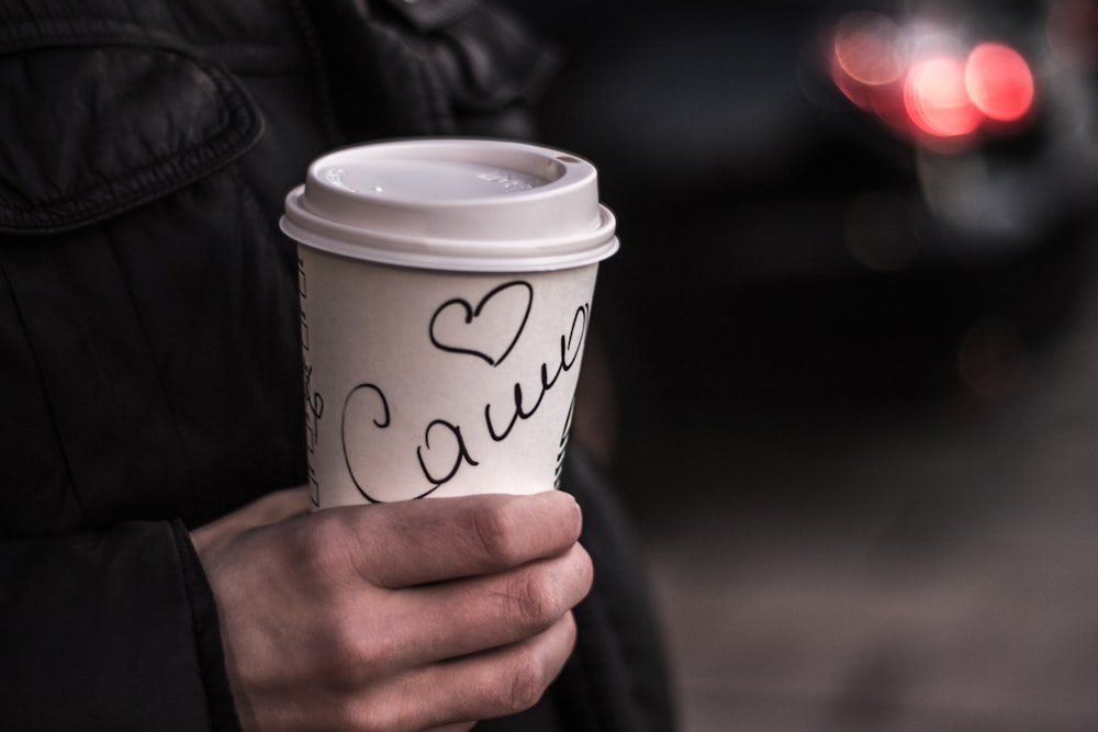 Persona che tiene la tazza di caffè bianca