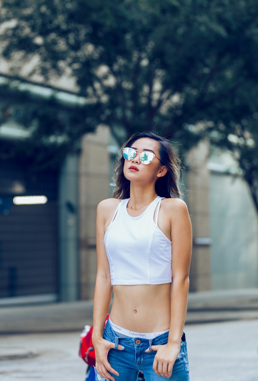 woman wearing blue denim jeans and white sleeved less dress and sunglasses