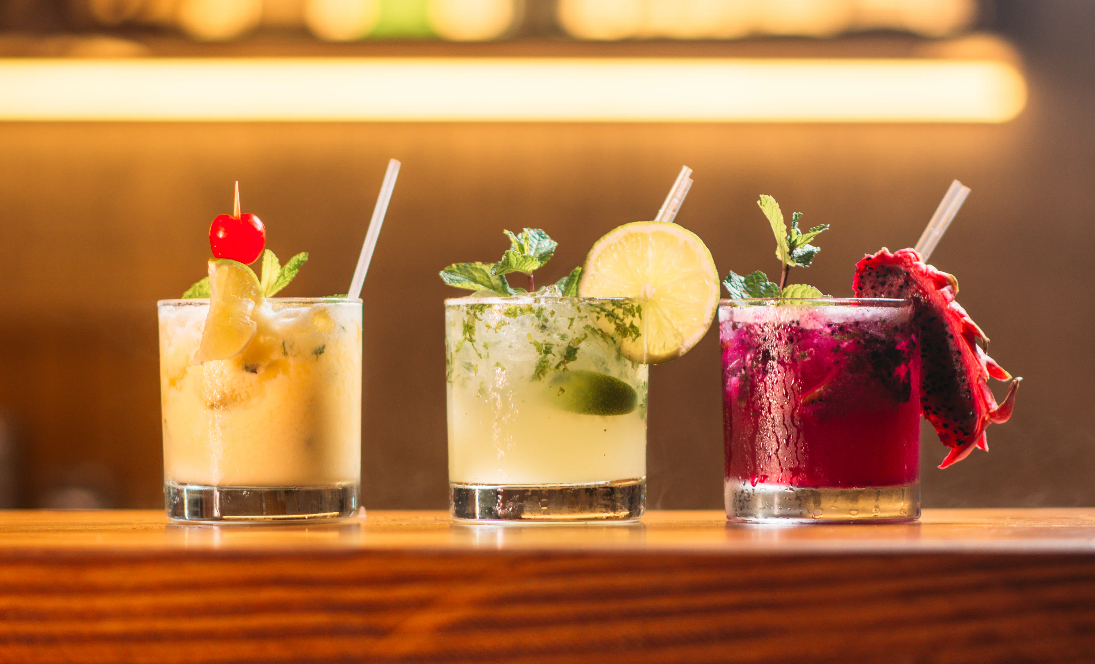 Three colourful cocktails lined up on the bar