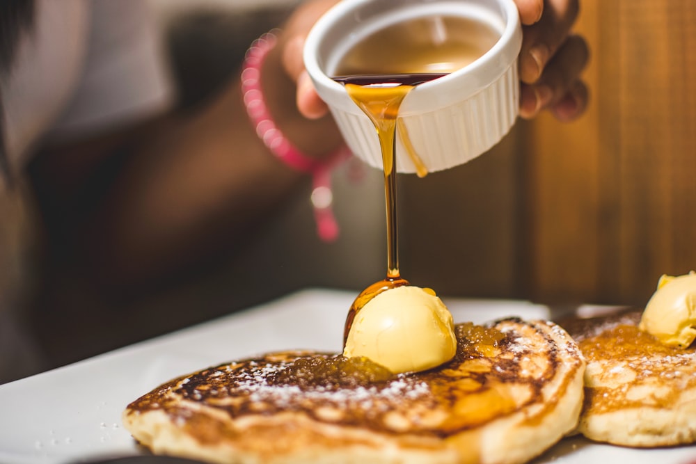 person pouring syrup into pancake