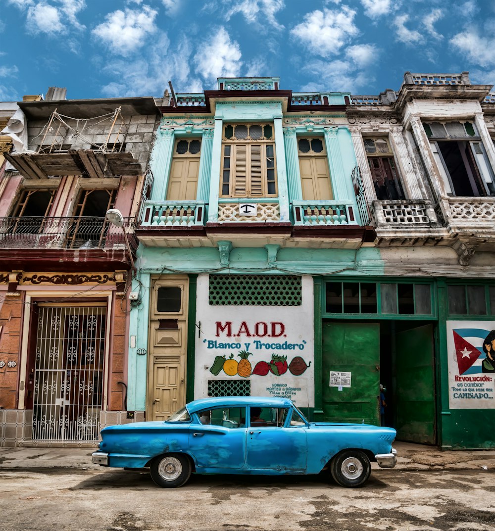 blue car parked beside green and gray house