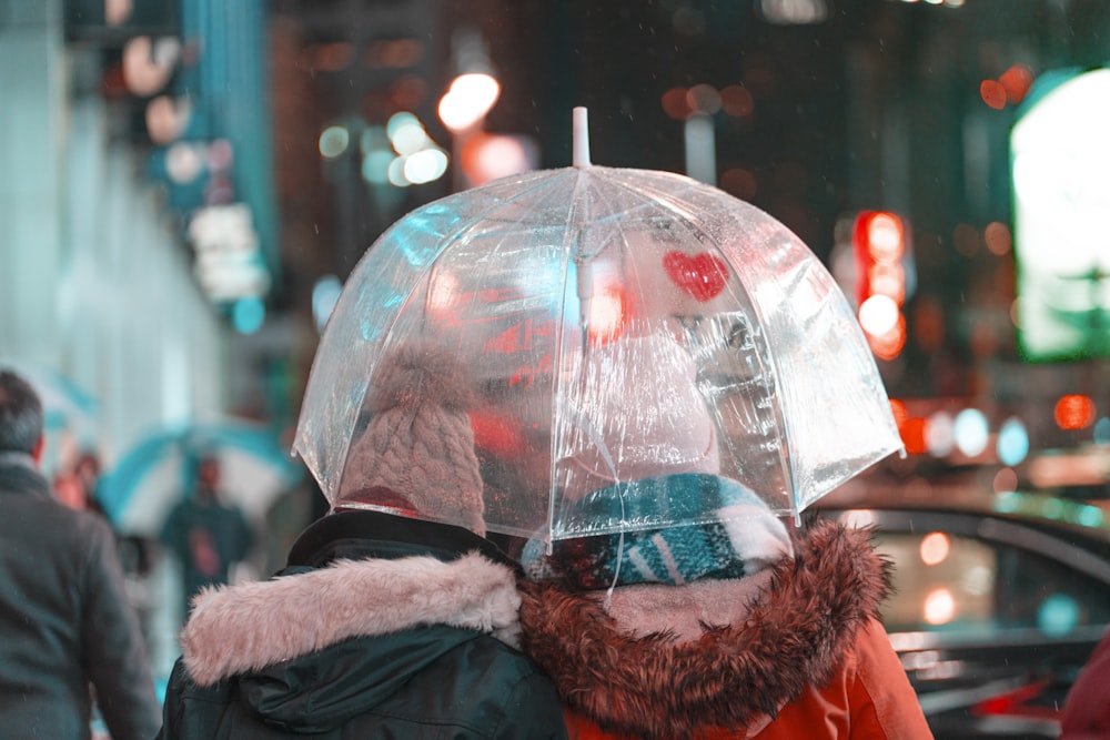 two person wearing coat holding white umbrella