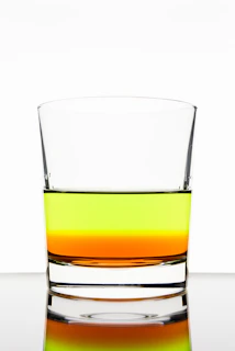 Colorful liquids layered in a transparent container demonstrating density differences.