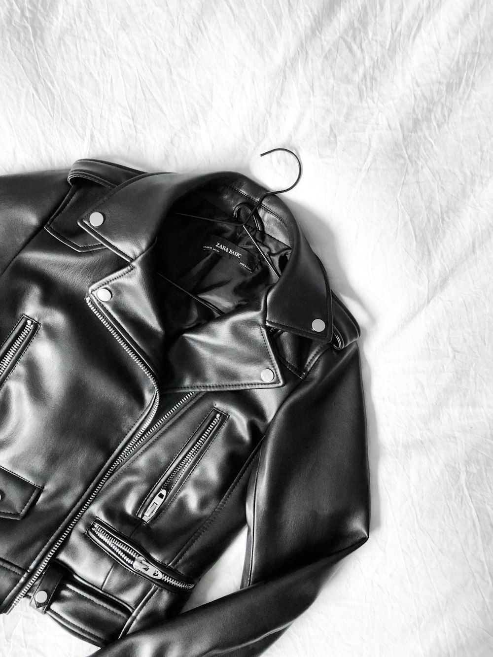 black leather zip-up jacket on white textile