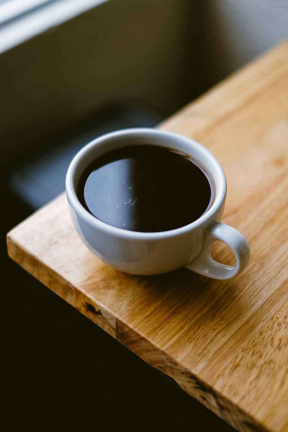 茶色の木製のテーブルに白いコーヒーカップ