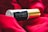 A bottle of 'Midnight Eau De Parfum' is resting on a rich, red fabric. The bottle features a sleek black and gold design, creating a luxurious and elegant aesthetic.