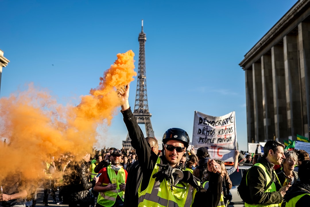 man standing and raising orange smoke on Paris during daytime