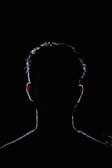 A dark silhouette looming behind a person who looks unaware and vulnerable.