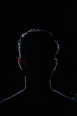 A dark silhouette looming behind a person who looks unaware and vulnerable.