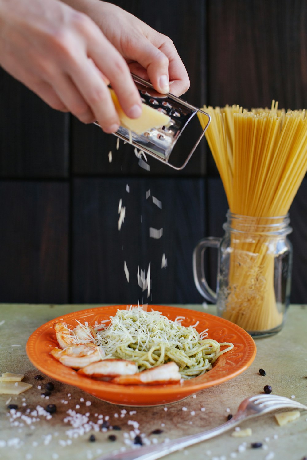 person grates cheese on top of pasta