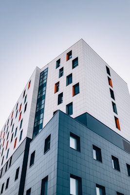 Modern multi-story building with a mix of white and blue panels, featuring orange window accents, relevant to property management and rental investment in Smyrna, Georgia.