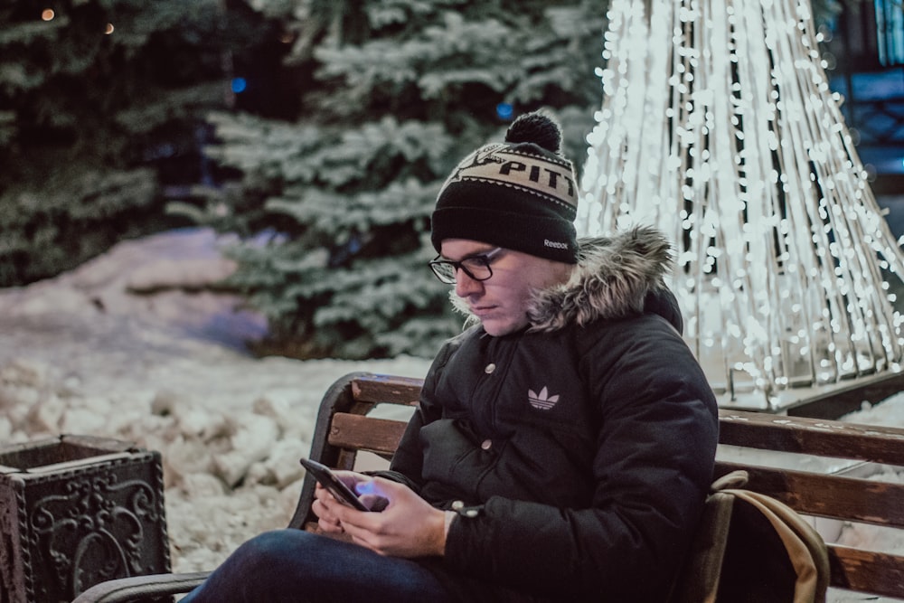 man using smartphone while sitting on bench