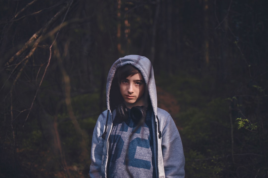 man wearing blue hooded jacket standing on forest