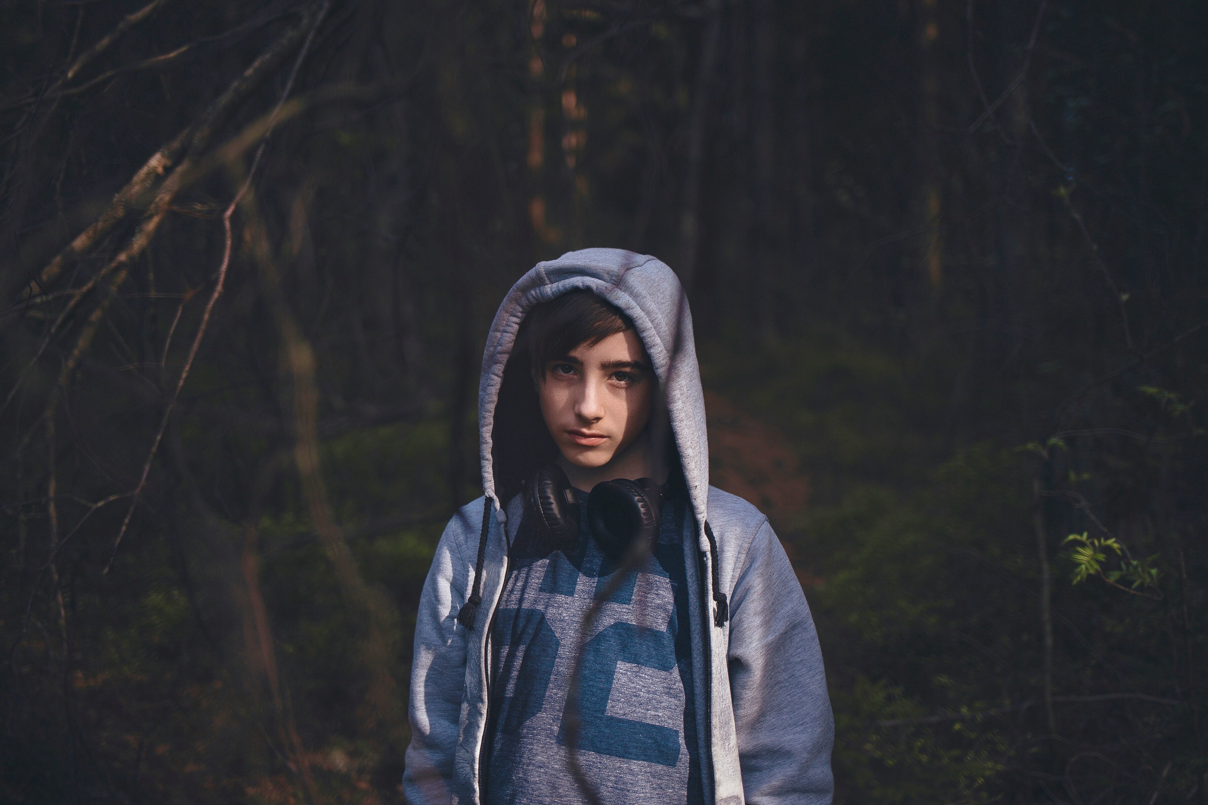 man wearing blue hooded jacket standing on forest