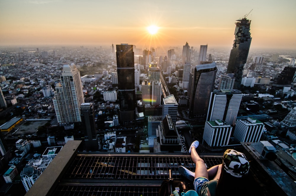 a person sitting on a ledge overlooking a city