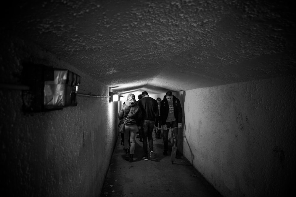 grayscale photography of men crossing tunnel