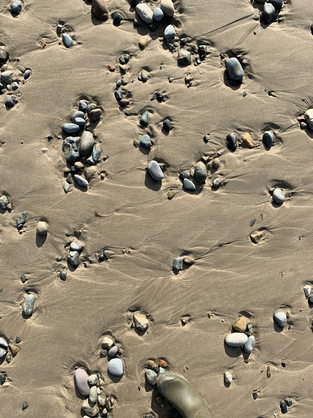 assorted pebbles on sand during daytime