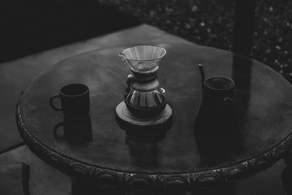 gray scale photo of mugs on round wooden table
