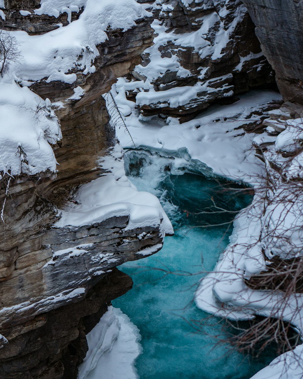 body of water under snow covered rock formations