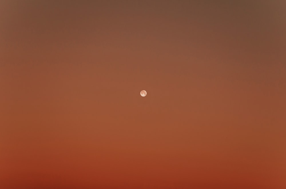 a red sky with the moon in the distance