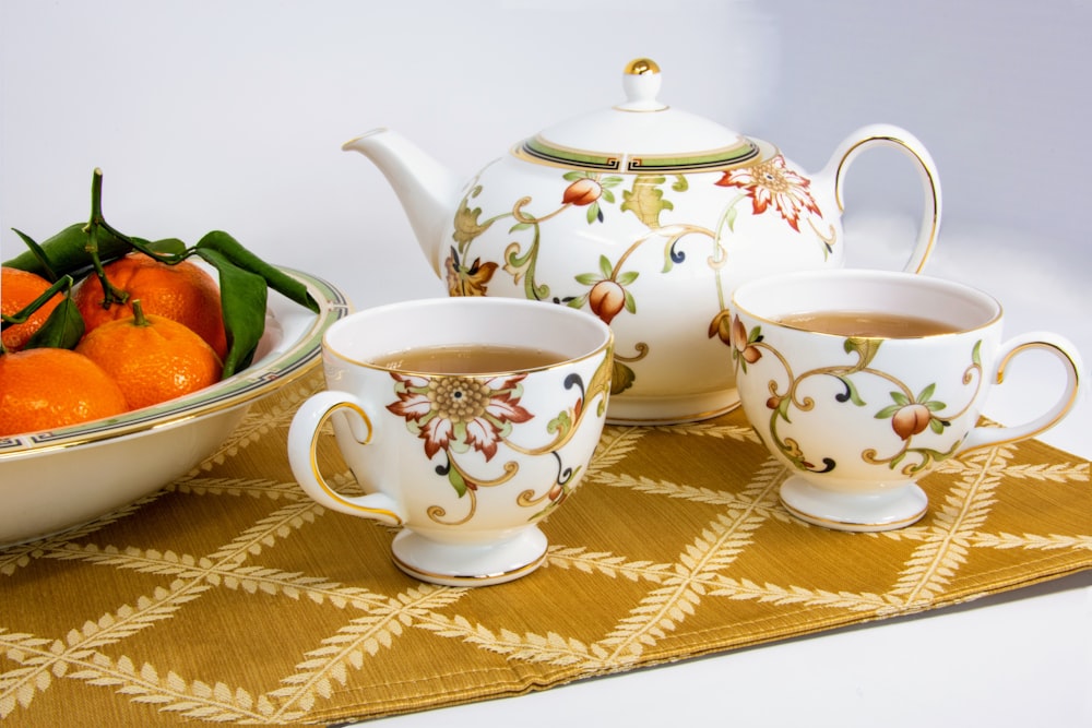 tazas blancas y multicolores llenas de té junto a frutas