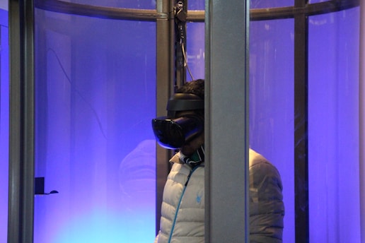 Close-up of a person wearing VR goggles inside a flight simulator cockpit with blue and red lighting.
