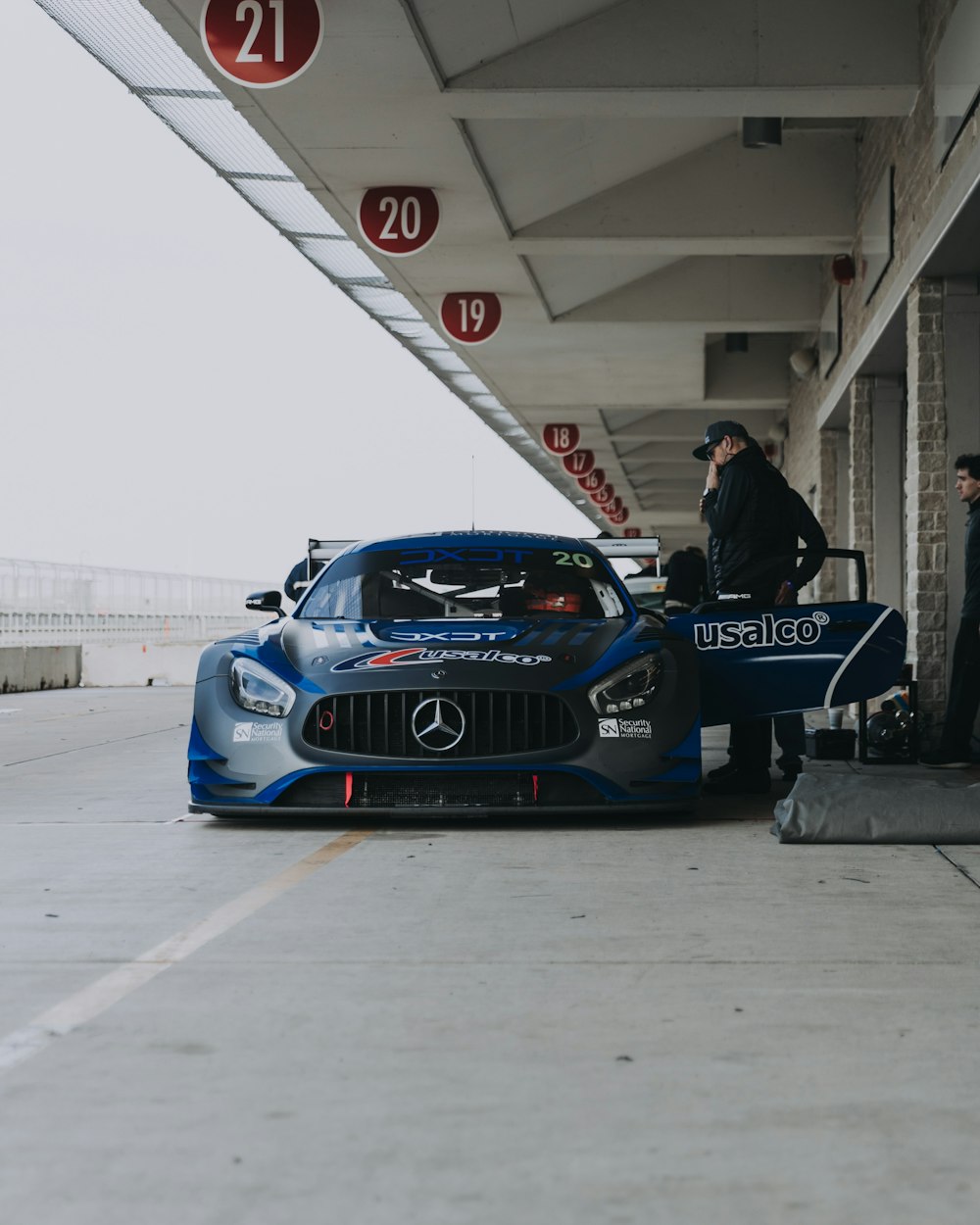 person wearing black jacket besides blue Mercedes-Benz car