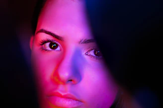 Close-up of a relaxing facial treatment with soft purple and pink lighting.