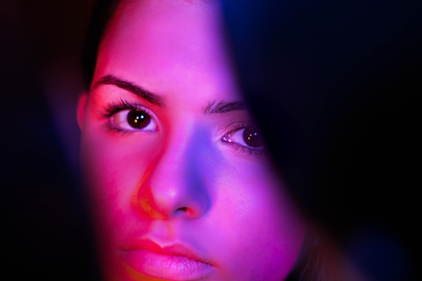 A vibrant, intimate close-up of a cam girl engaging with her audience, bathed in soft, colorful lighting.