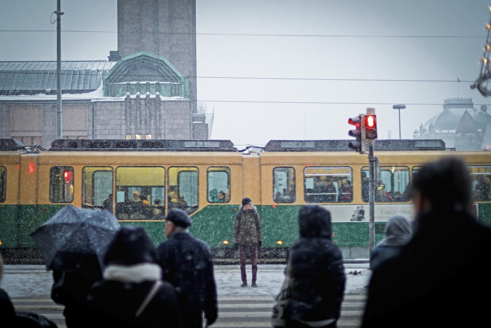 man standing beside yellow and green subway