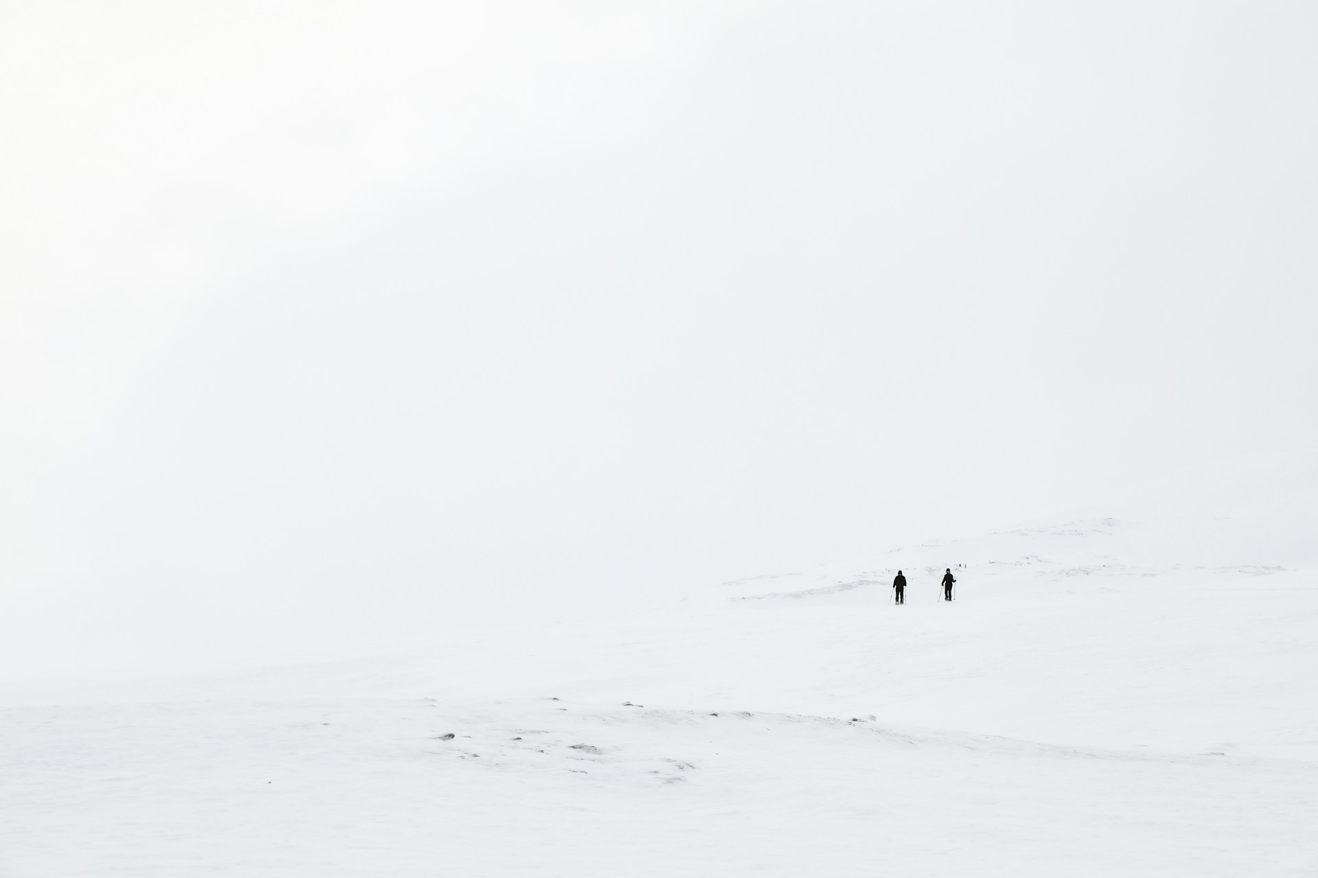 a couple of people walking across a snow covered field