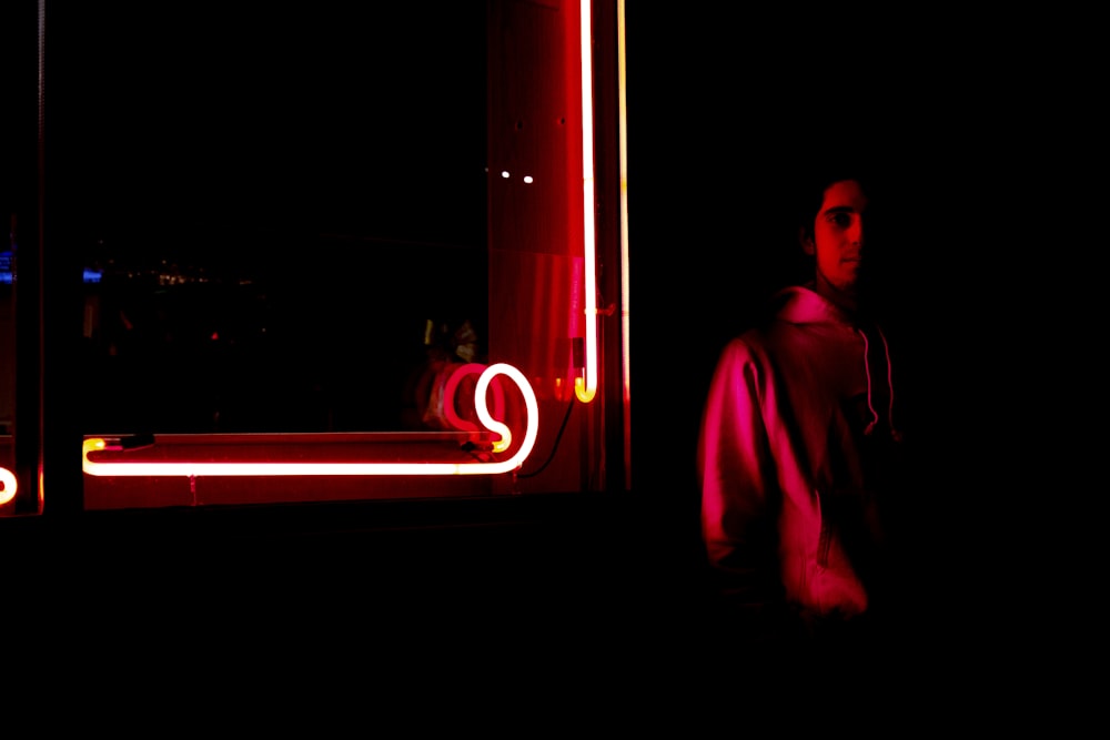 man standing near red neon light