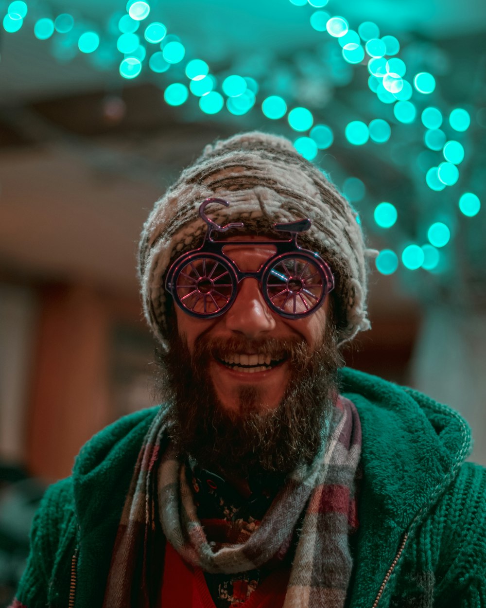 selective focus photography of man wearing gray knit cap, red-and-gray scarf and green cable knit zip hoodie