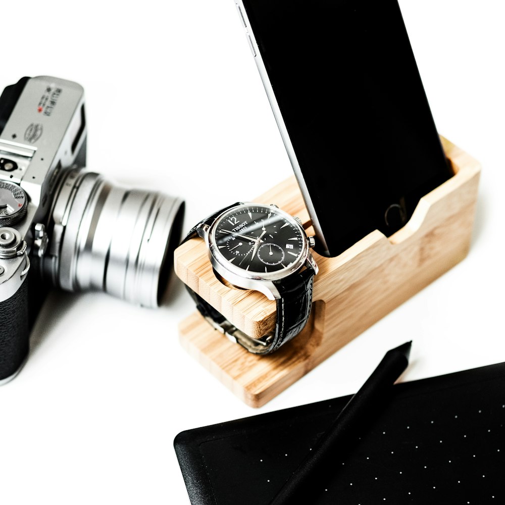 round silver-colored and black chronograph watch with leather band and iPhone